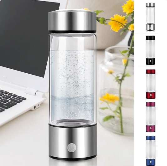 Clear water bottle with silver top on a desk next to a laptop and flowers