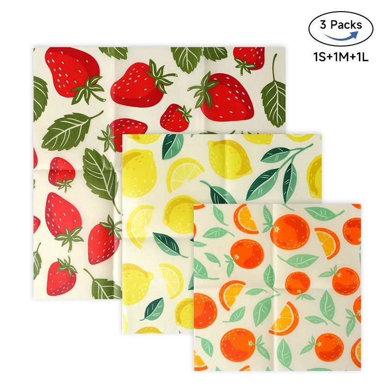 Set of three reusable food wraps with strawberry, lemon, and orange patterns on a white background.