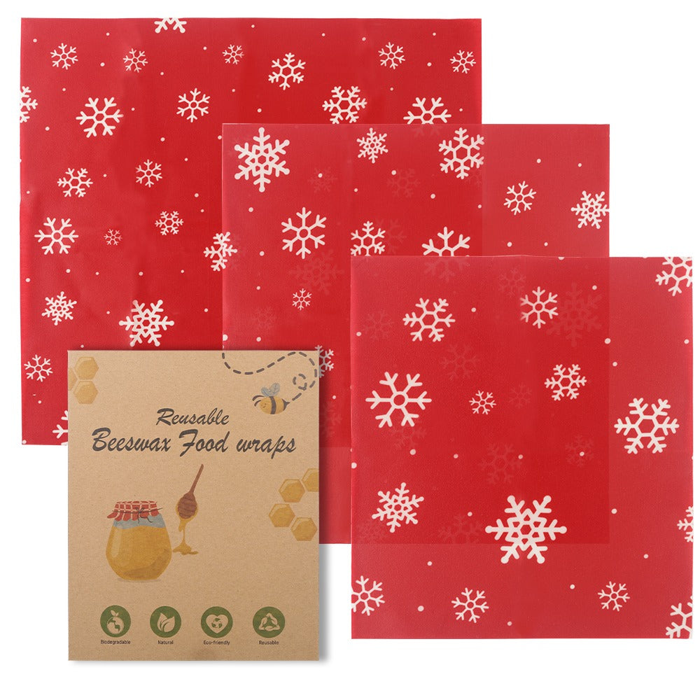 Red reusable beeswax food wraps with snowflake pattern and a cardboard packaging on a white background